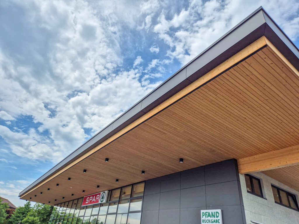 Auskragendes Holzdach am Supermarkt – wettergeschützter Eingangsbereich SPAR Heimschuh